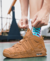 Brązowe wysokie buty do koszykówki sznurowane na nogach na boisku