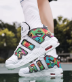 Białe sneakersy koszykarskie z graficznym wzorem na nogach w powietrzu